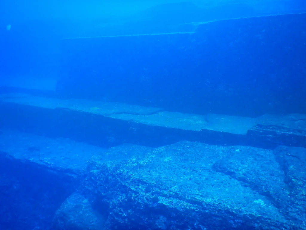Buzo explorando las terrazas de arenisca del Monumento Yonaguni bajo el agua cristalina frente a la isla de Yonaguni, Japón