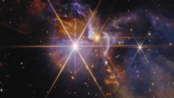 Imagen en infrarrojo del telescopio James Webb del sistema FS Tau, con protoestrellas FS Tau A y FS Tau B y chorros de material sobrecalentado en naranja y rojo sobre un fondo de galaxias distorsionadas por el polvo